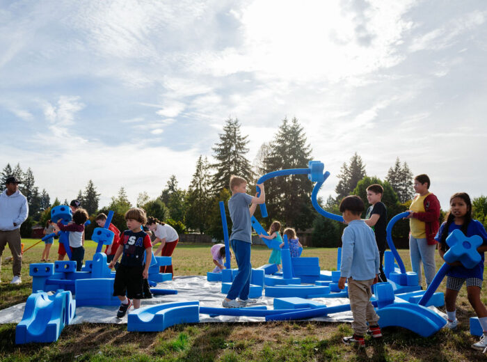 Children building with large foam blocks at a park.