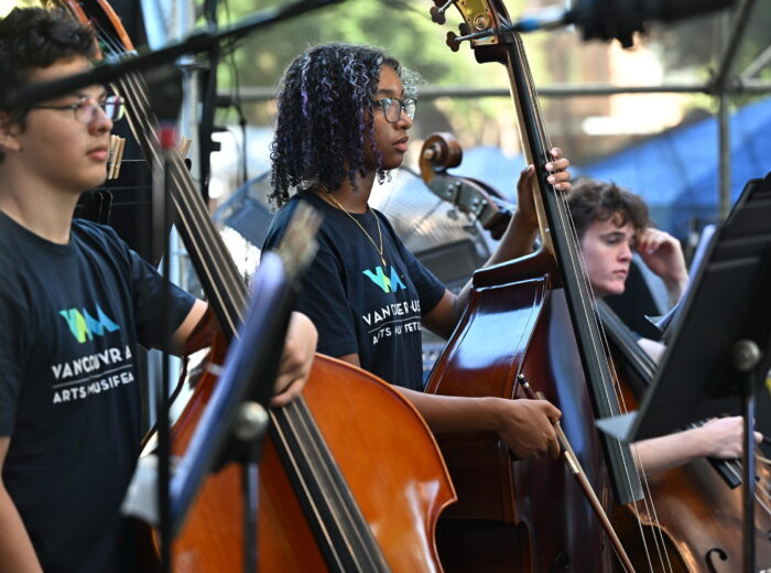 Youth double bass players preparing to play on stage.